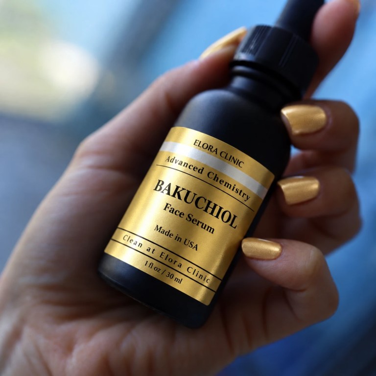 A hand holding a dropper bottle of Elora Clinic Bakuchiol Serum.
